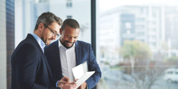 Shot of two businessmen using a digital tablet together at work  Our Services dl